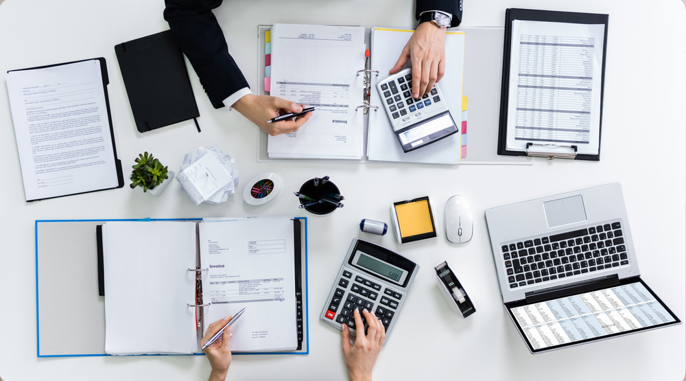 High,Angle,View,Of,Two,Businesspeople,Calculating,Bills,In,Office